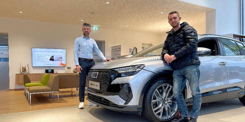 2 Vertriebsmitarbeiter mit einem Audi Q4 e-tron